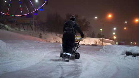 night snow removal at park with ferris wheel