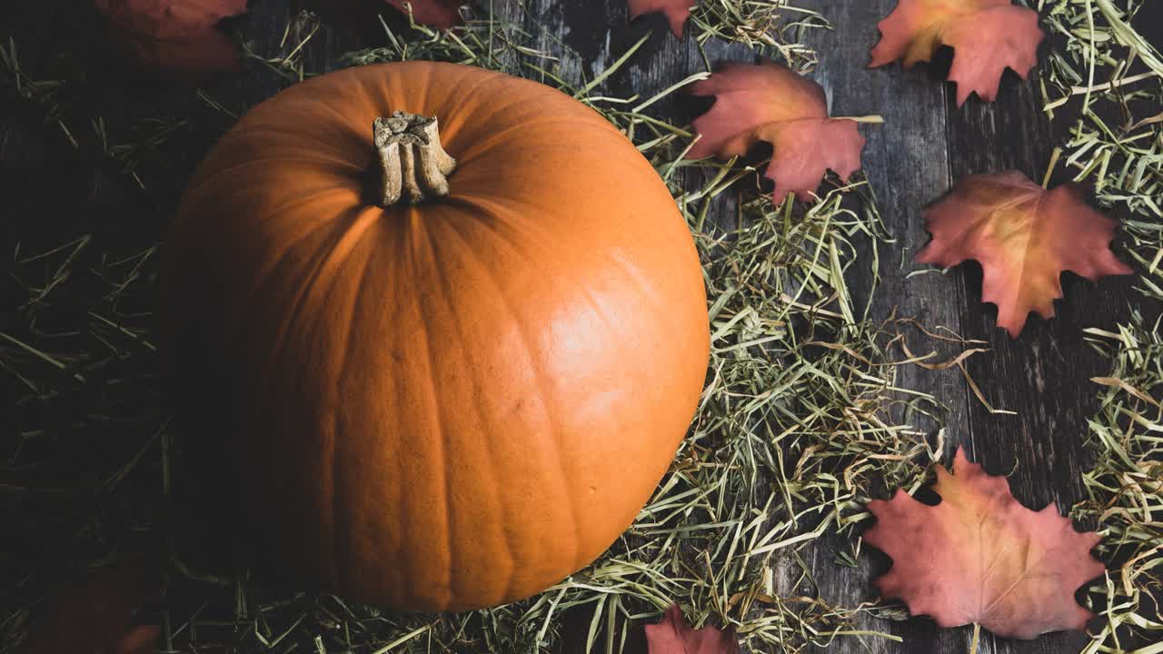 gran calabaza naranja decorativa rural en un fondo de madera rústica con heno rural y follaje de otoño como decoración festiva de vacaciones para acción de gracias o halloween