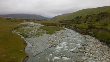 small creek flowing through a bigger river bed coming from the mountains in mackenzie, new zealand