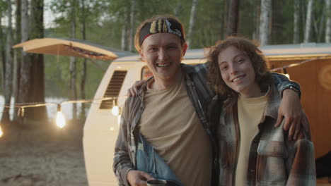 portrait of joyous man and woman embracing at campsite