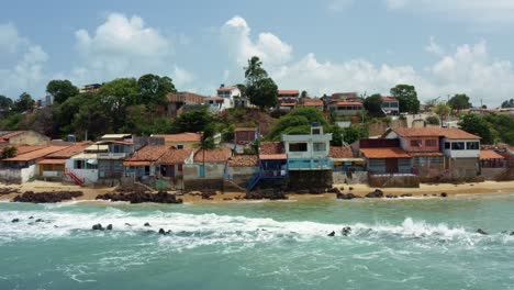 Aerial-drone-shot-of-small-beach-homes-along-the-coast-of-the-famous-tropical-Baia-Formosa-beach-with-small-waves-crashing-into-the-shore-in-the-state-of-Rio-Grande-do-Norte,-Brazil-on-a-summer-day