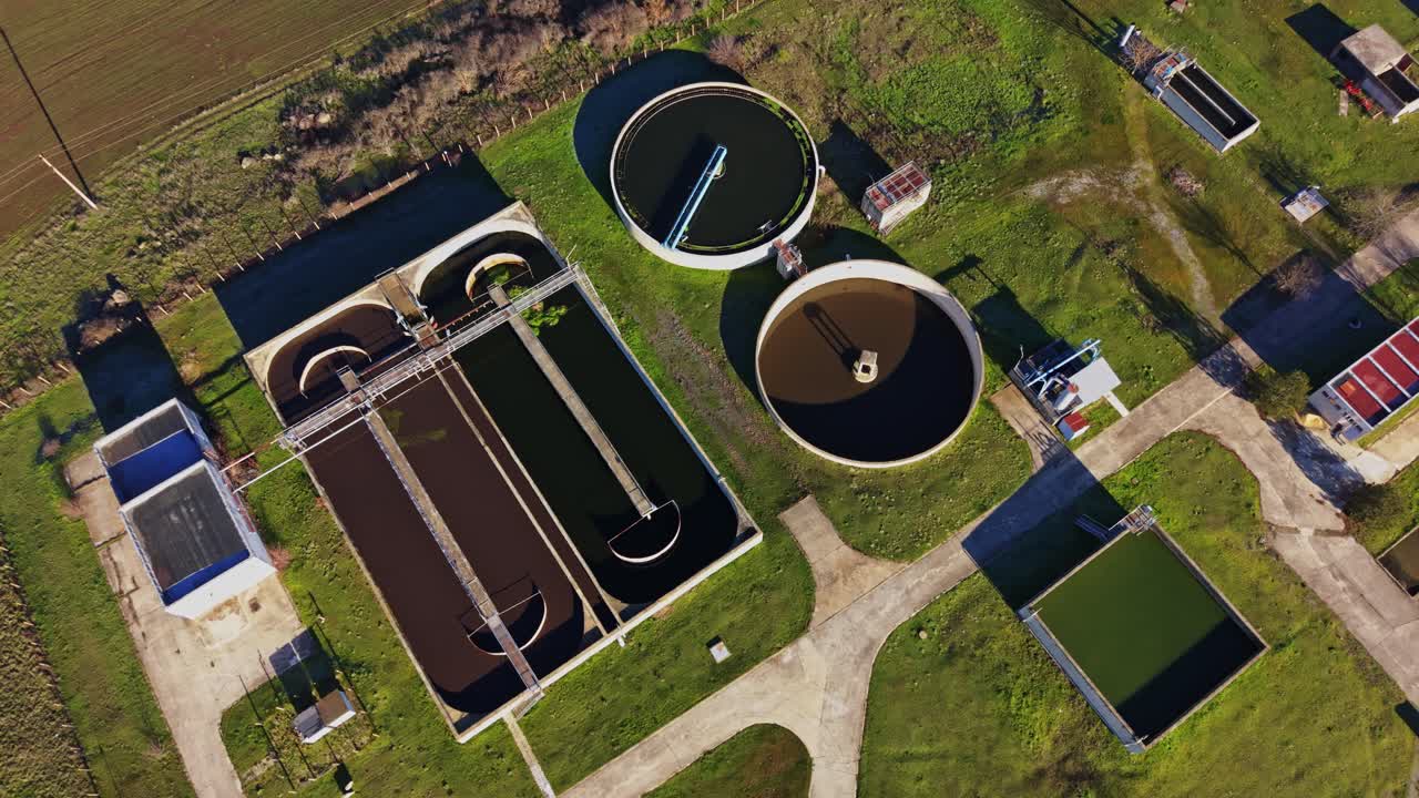 Water treatment facility with processing tanks and green fields nearby