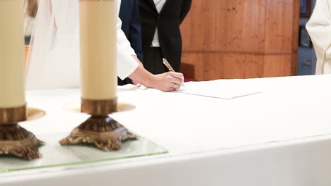 disparado a través de velas vintage de la novia con vestido blanco firmando el contrato de matrimonio