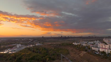 Aerial-wide-shot-over-big-forest-revealing-a-city-skyline-blending-seamlessly-with-the-natural-landscape-in-sunset-warm-light,-HDR-4K50Fps