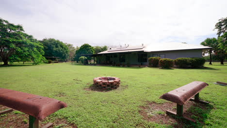 Bancos-Curvos-De-Bronce-Rodean-Una-Zona-De-Estar-Cerca-De-Una-Chimenea-De-Ladrillo-En-Una-Lujosa-Casa-Rural-En-El-Patio-Trasero-Al-Aire-Libre