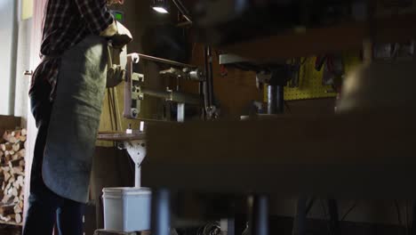 caucasian male knife maker in workshop using angle grinder