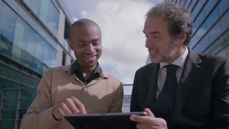 Uomini d'affari sorridenti che discutono con un tablet all'aperto.