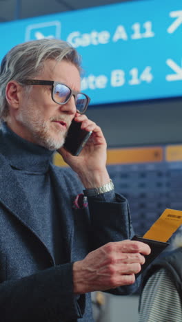 man at airport talking on phone and checking passport