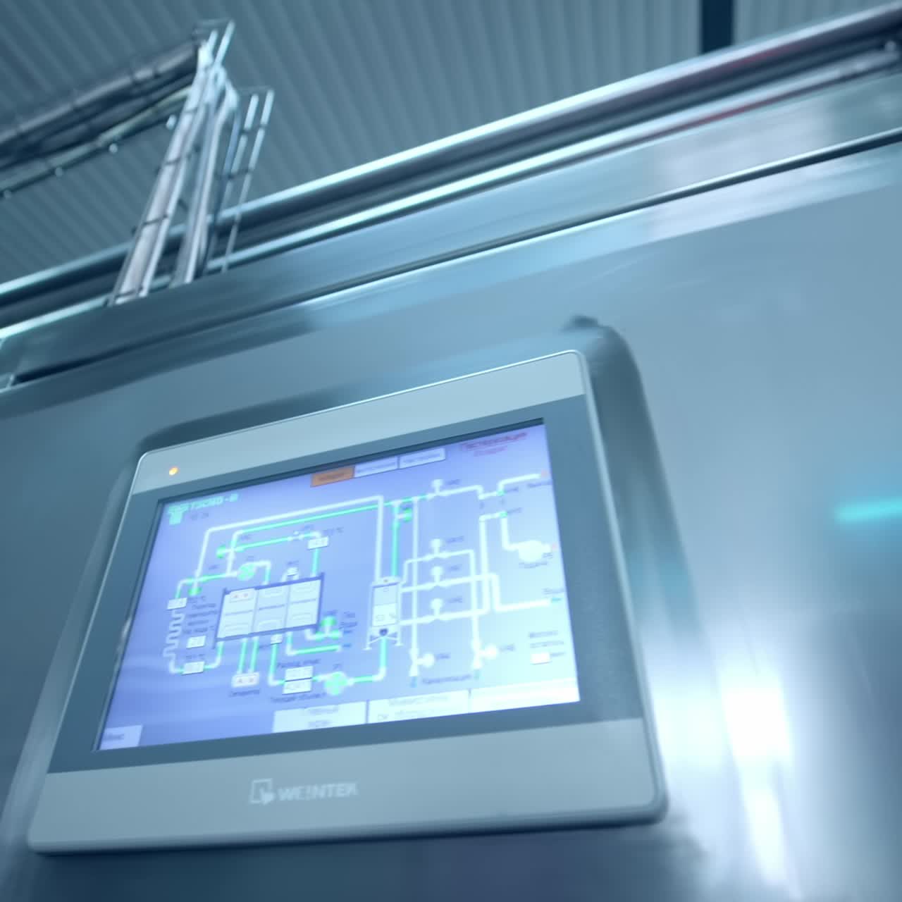 Stainless steel equipment at the diary manufacturing plant. Moving along the numerous pipes at the factory. Metal locker with a screen showing the system of pipelines