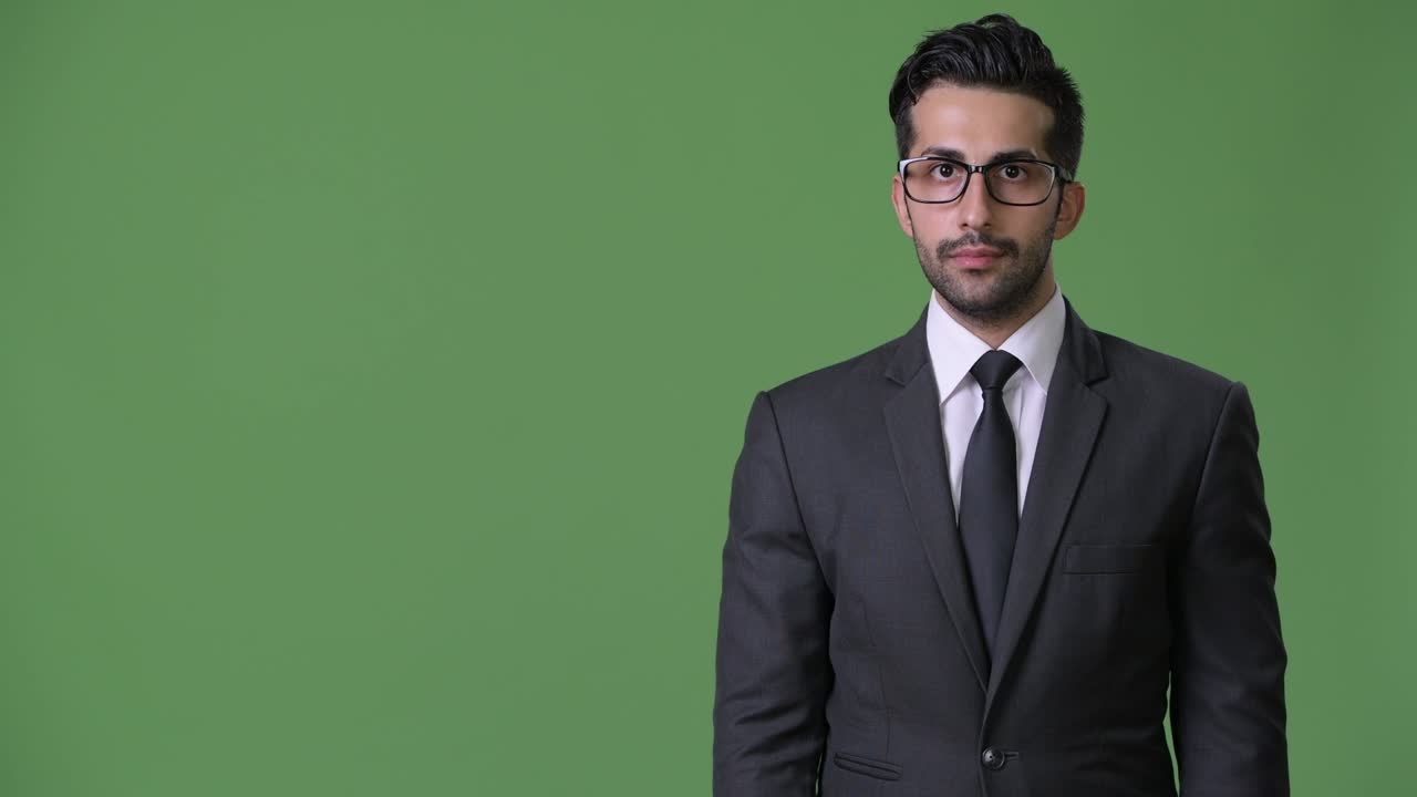 Jovem e bonito empresário persa barbudo contra fundo verde