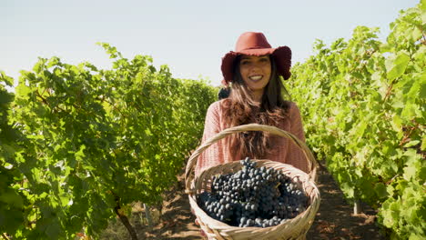 mujer sonriente levantando una canasta con uvas