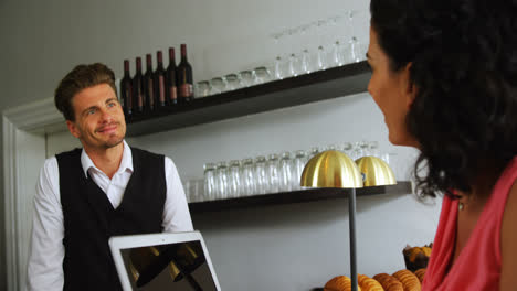 Bar-tender-interacting-with-woman-at-counter