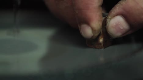 extreme close-up of lab testing a metal ingot. filing the ingot on a rotating horizontal filing plate