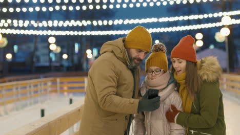 family selfie at an ice skating rink at night