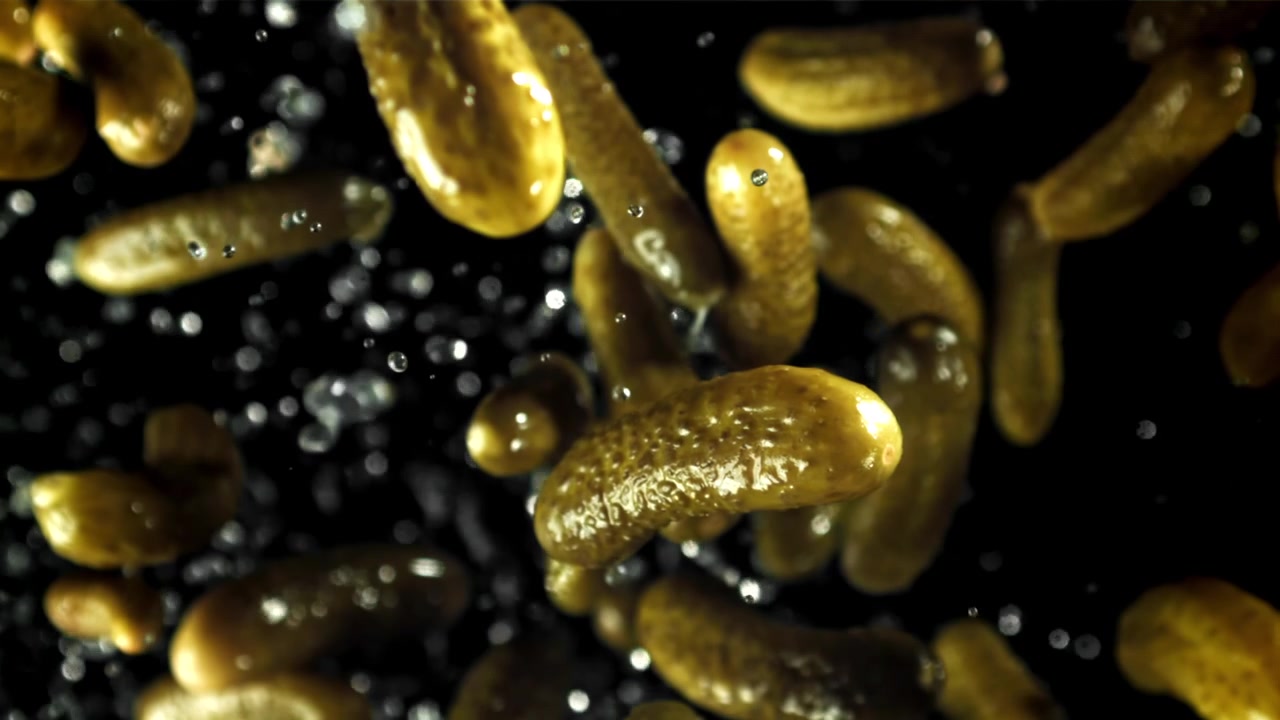 Cetrioli sottaceto in caduta al rallentatore con gocce d'acqua
