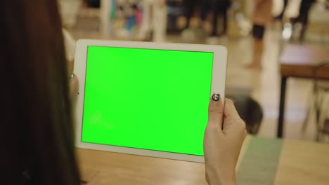 mujer con una tableta en la mano con una pantalla verde en blanco con una llave de croma leyendo noticias,