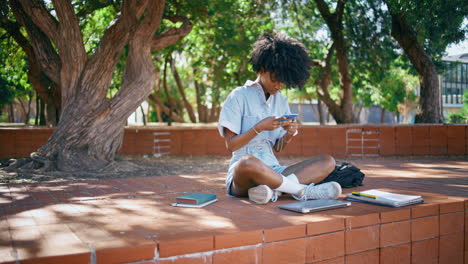 girl messaging cellphone sitting city park. teenager smiling reading sms