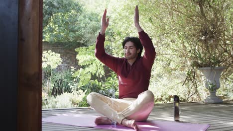 Caucasian-man-practicing-yoga-meditation-on-terrace-in-sunny-nature,-slow-motion