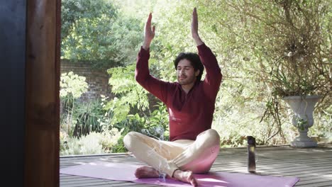 caucasian man practicing yoga meditation on terrace in sunny nature, slow motion
