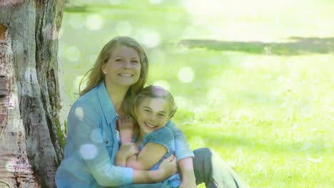 Animation-of-glowing-spots-over-happy-caucasian-mother-with-daughter-cuddling-in-garden