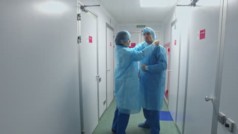 Trabajadores-De-Laboratorio-Con-Uniforme-Protector.-Científicos-Vistiendo-Bata-De-Laboratorio-En-El-Pasillo.