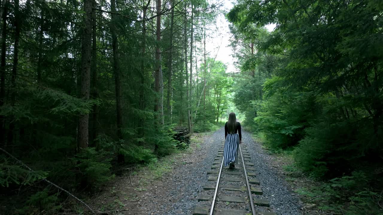 Lonely girl walks along the tracks in the forest