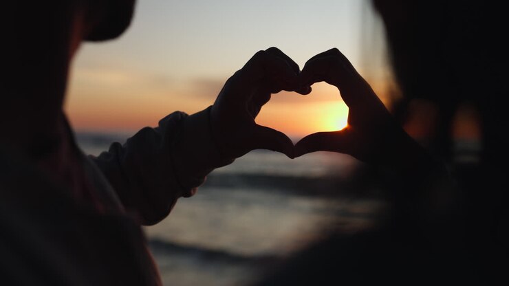 Silhouette, tramonto e mani di coppia con cuore