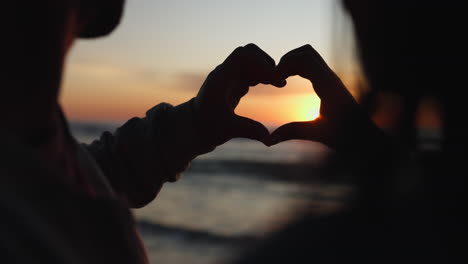 silhouette, sunset and hands of couple with heart