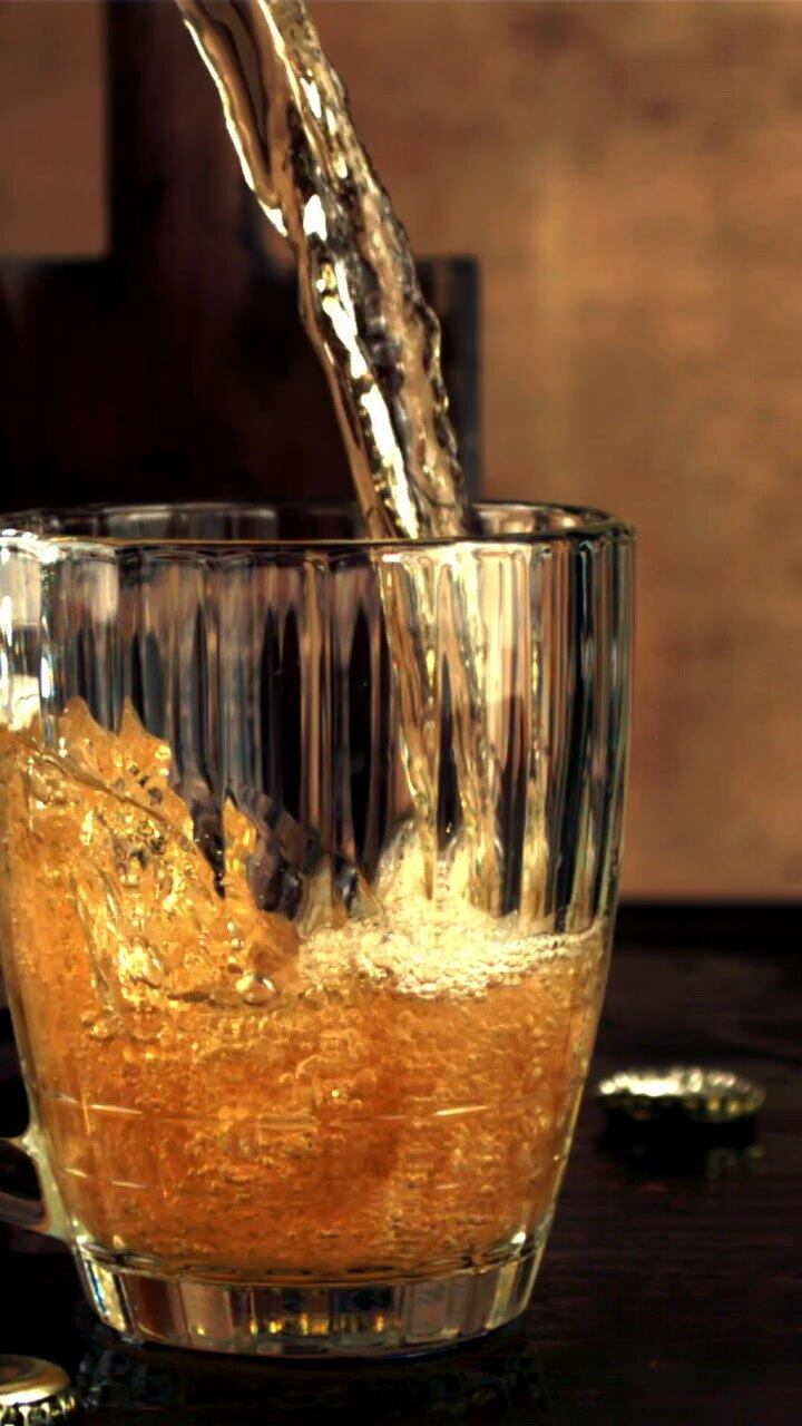 Slow Motion Pouring of Golden Beer into a Glass Mug