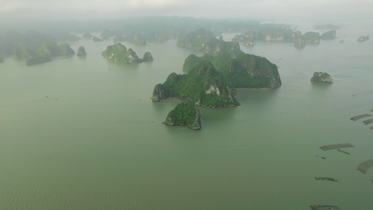 Aerial view of numerous limestone islands in a misty bay, reminiscent of Halong Bay