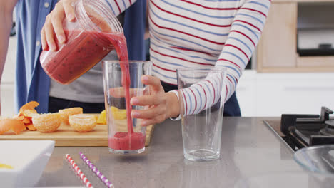 video of midsection of diverse couple pouring juice into glasses