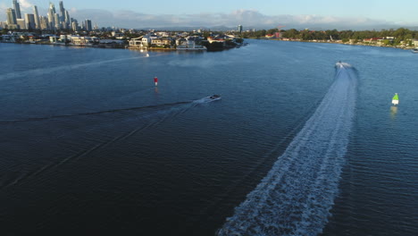 aerial view following a boat and jet ski along the board waters of southport gold coast australia during sunrise.