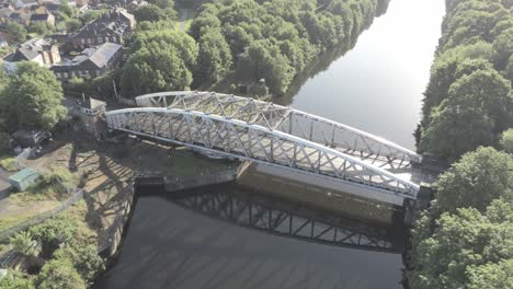 scenic old-fashioned steel arched traffic footbridge orbit right over manchester ship canal at sunrise