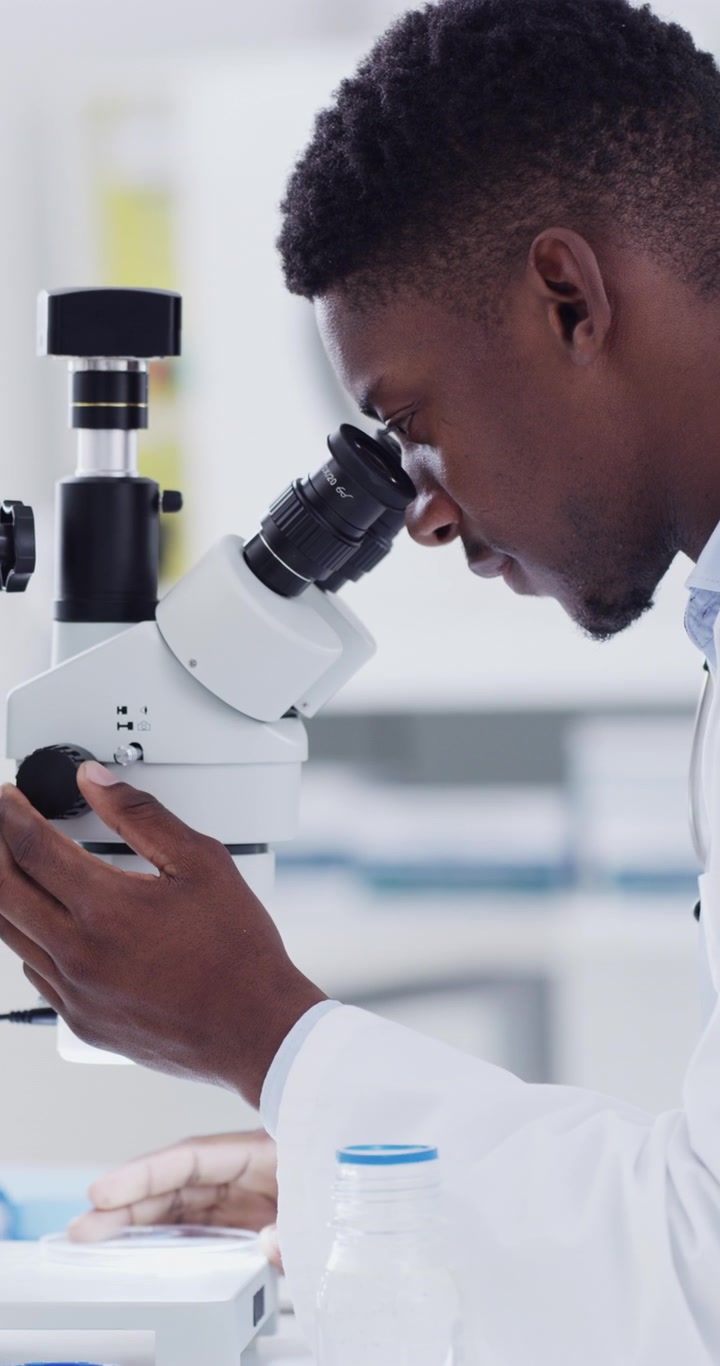 Scienziato uomo che esamina campioni al microscopio in laboratorio