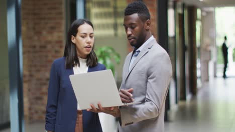 two happy diverse business people working together, using laptop in modern office