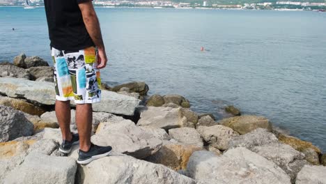 man standing on rocks by the ocean