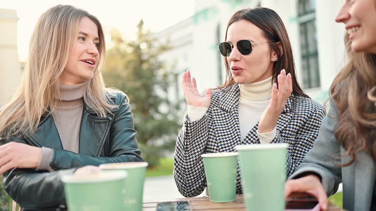 Three women talking and drinking coffee at a terrace