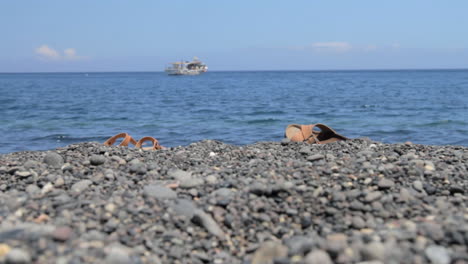 two pairs of leather sandals on a black peddle beach in santorini, called kamari