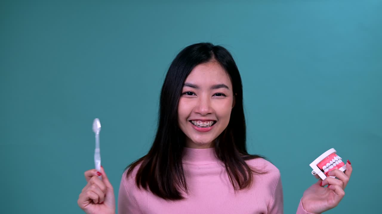 푸른 스크린 배경에 정형 치과 장치를 착용 한 미소 짓는 아시아 여성. 치과 관리와 건강한 치아.