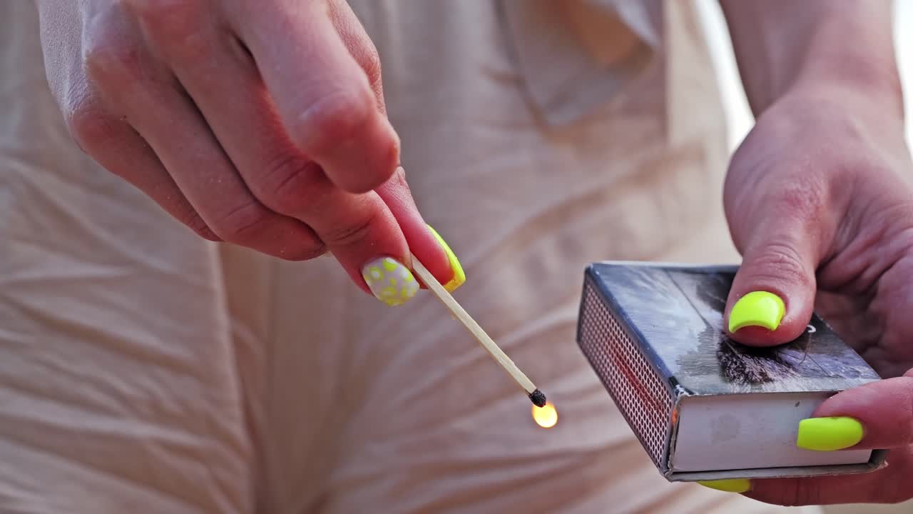 Slow motion shot of match igniting in summer light, hands detailed and steady