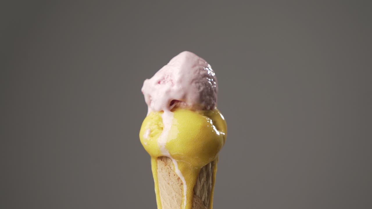 Yellow and pink Ice cream cone gradually melting on isolated background. Sugar concept. Time lapse