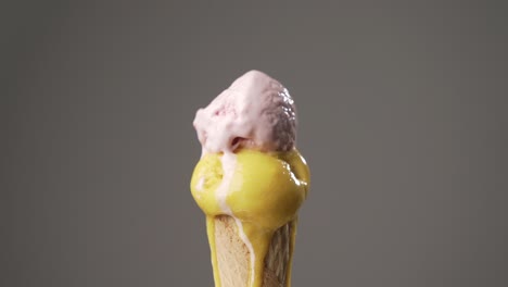 yellow and pink ice cream cone gradually melting on isolated background. sugar concept. time lapse