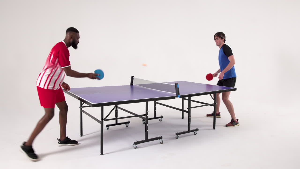 Playing table tennis, two men competing in friendly match indoors
