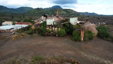 zoom de la fábrica de azúcar de koloa con montañas en el fondo, drone aéreo