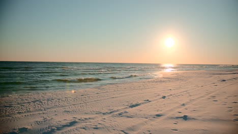shots of the ocean on a warm, sunny evening with footprints in the sand facing the sun directly-1