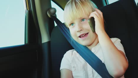 funny girl  speaks on the phone, rides in the back seat of the car. it is fastened with a seat belt