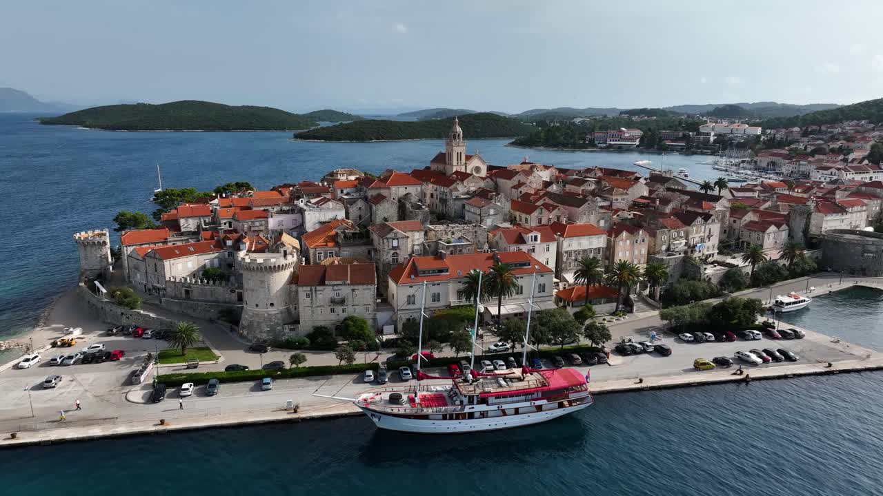 Korcula Old Town with red-roofed buildings and surrounding sea. Drone aerial, pan right