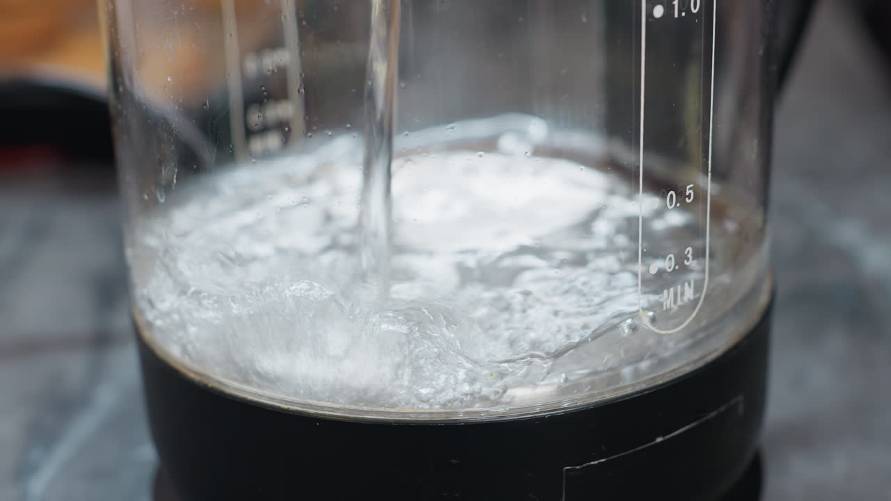 물이 여있는 전기 물 항아리의 클로즈업, 물에 눈에 띄는 거품이 형성되고 항아리에 명확한 문구, 미니멀한 장식으로 현대 부에서 포착