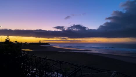 vívido amanecer violeta violeta sobre una playa relajante con algunas olas en portugal