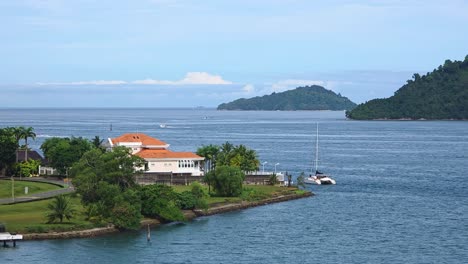 catamaran cruising by a high-class residential area near waterfront of kota kinabalu in sabah, malaysia. wide static shot